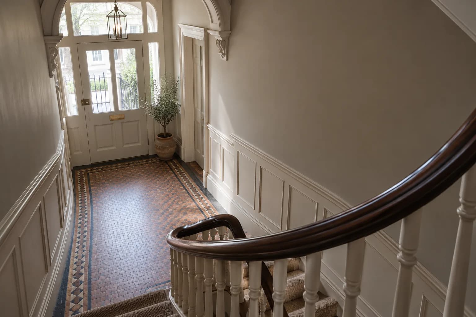 Converted-house entrance hall with a curved timber stair and painted wall panelling